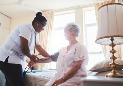 Nurse checking vital signs of a senior resident in a room