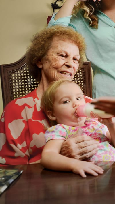 Senior resident smiling with a child at a table