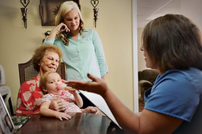 Resident interacting with family and staff in a cozy room