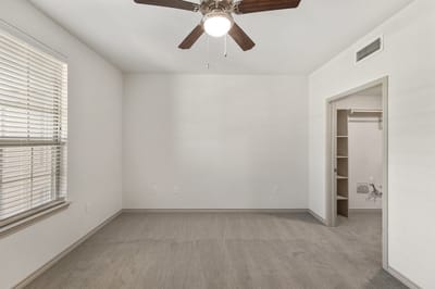 Empty resident room with a ceiling fan and carpeted floor
