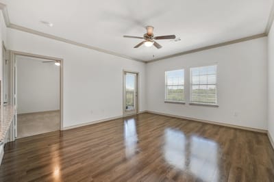 Bright, empty room with wooden flooring and ceiling fan