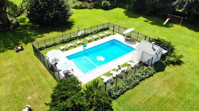 Aerial view of a pool surrounded by green lawn and seating