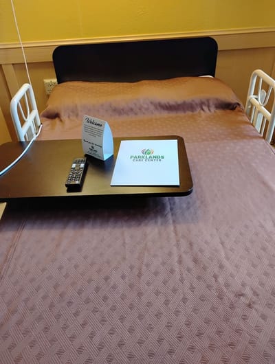 A neatly made hospital bed with welcome signage