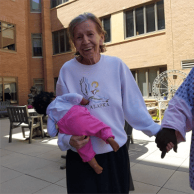 Resident enjoying the outdoor courtyard with a doll