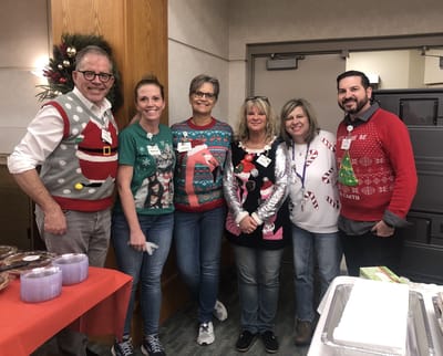 Staff members in festive sweaters at a holiday event