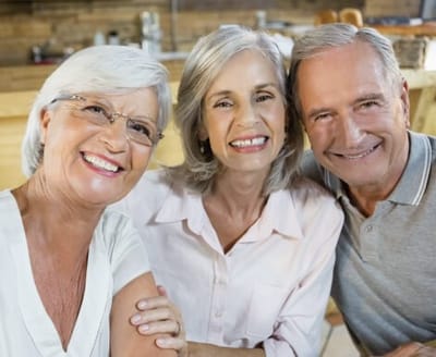 Lynridge, assisted living in Murphy, TX — Three smiling seniors posing together in a warm setting