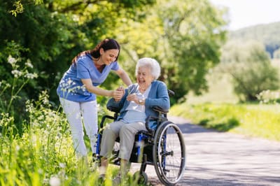 Caregiver assisting a resident in a wheelchair outdoors