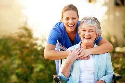 A caregiver and resident smiling together outdoors