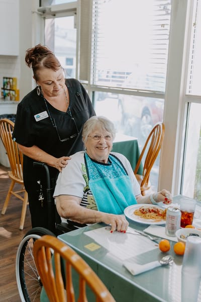 Resident enjoying a meal with staff assistance