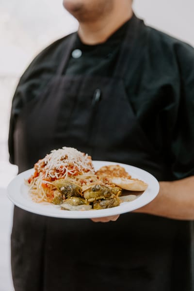 Chef presenting a plate of spaghetti and vegetables