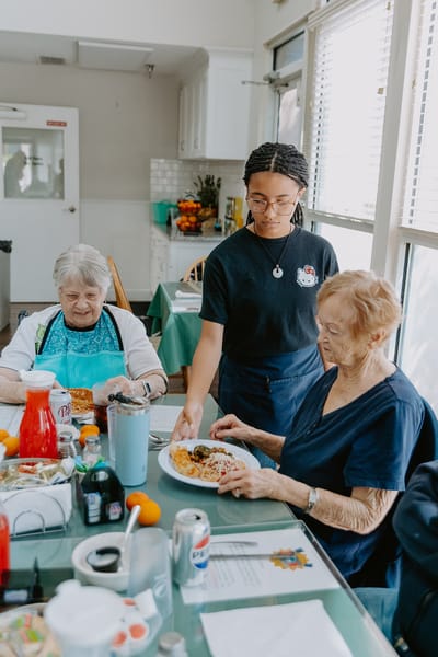 Residents enjoying a meal with staff assistance