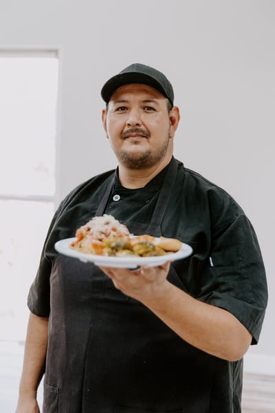 Chef presenting a plate of food in a dining space