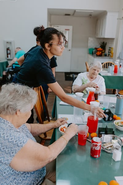 Residents enjoying a meal with staff assistance