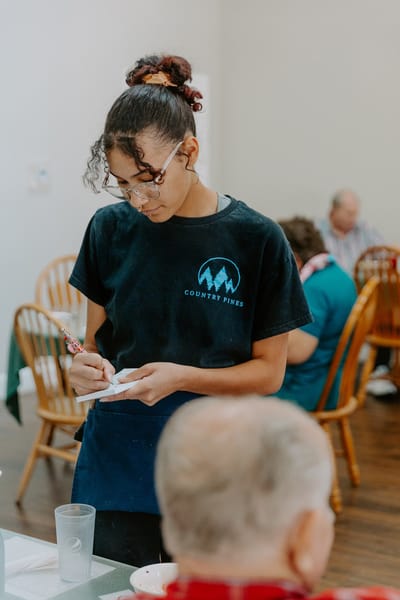 Staff member taking notes in a dining area.