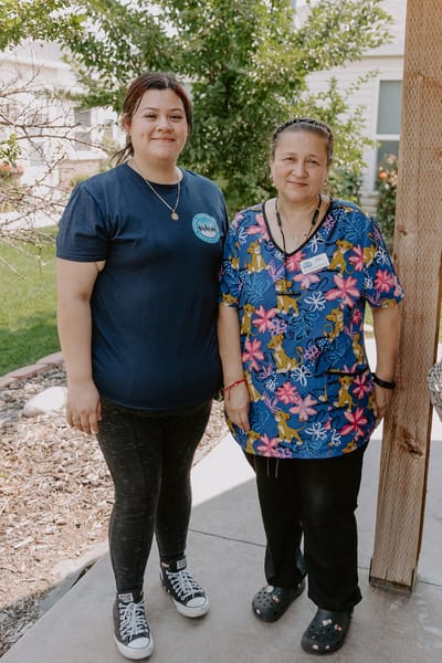 Two caregivers posing outside the facility