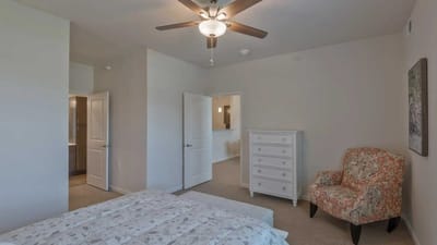 Cedar Ridge Village, nursing home in West Des Moines, IA — Cozy bedroom with floral armchair and ceiling fan