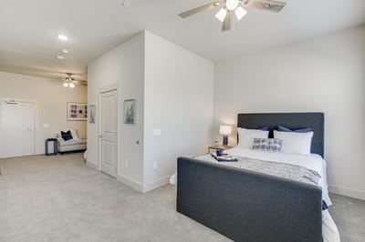 Clean and spacious resident bedroom with bed and fan