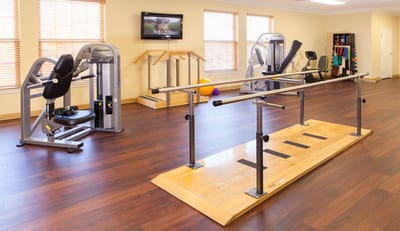 A fitness room with exercise equipment and rehabilitation bars