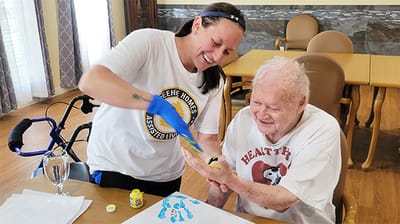 Resident enjoying a painting activity with staff
