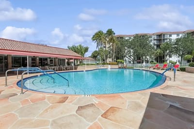 Outdoor pool area with lounge chairs and palm trees
