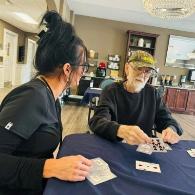 A staff member and resident playing cards together