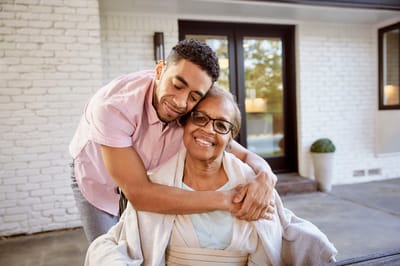 A caregiver embracing a resident outside a facility