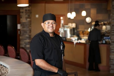 Staff member in a dining area with coffee bar