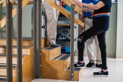 Staff assisting a resident on stairs during therapy