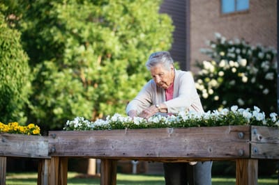An elderly woman gardening at Friendship Assisted Living.
