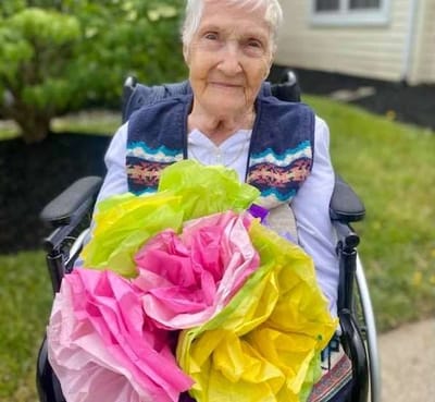Resident in a wheelchair holding colorful tissue paper flowers