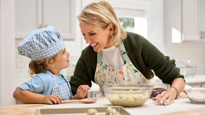 A woman and child baking together in a bright kitchen.