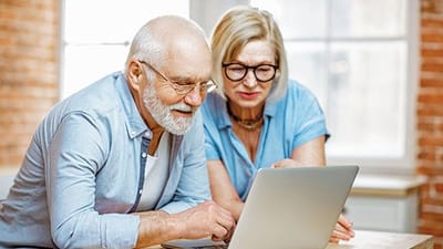 Two seniors engaging with a laptop in a bright interior