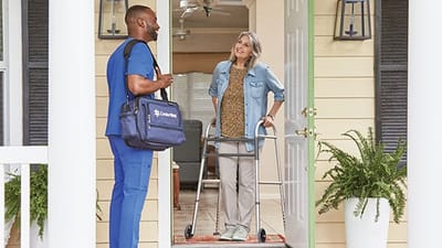 Healthcare staff assisting a resident at the front door