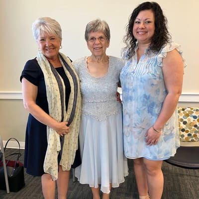 A resident celebrating with two staff members in a common area