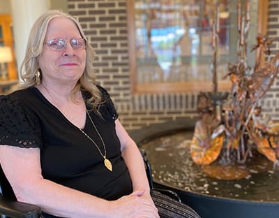 Resident sitting by a decorative water feature in the facility
