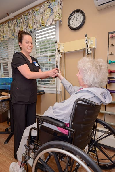 Staff assisting a resident with rehabilitation exercises