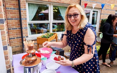 A staff member serving food at a festive outdoor event