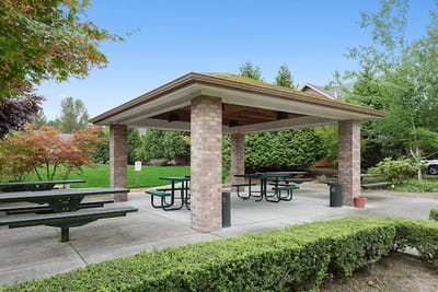 Outdoor gazebo with picnic tables and greenery