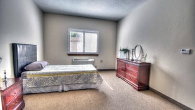A private resident room with a bed and dresser