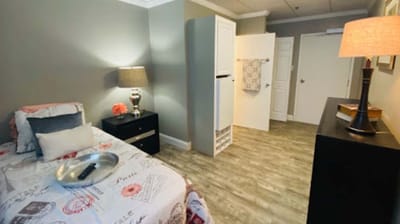 A cozy resident room with a bed and lamp