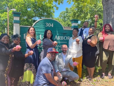 East Lake Arbor, Nursing Home in Decatur, GA — Group of people holding peaches near a sign