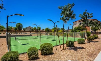 Outdoor tennis courts with landscape and building in view