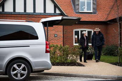 A couple leaving in front of a facility with a vehicle