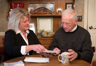 Caregiver assisting a senior man at a table