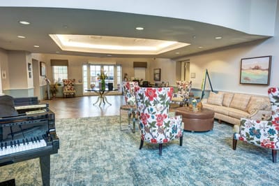 Bright common area with floral chairs and piano