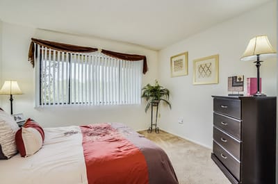 Bright interior of a resident room with a bed and dresser
