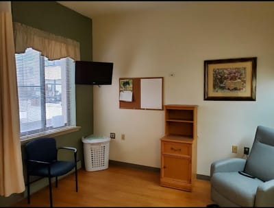 A resident room with a chair, desk, and window