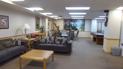 Bright common area with seating and tropical paintings