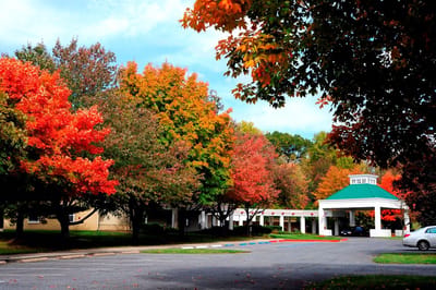 Exterior view of a senior living facility surrounded by autumn trees