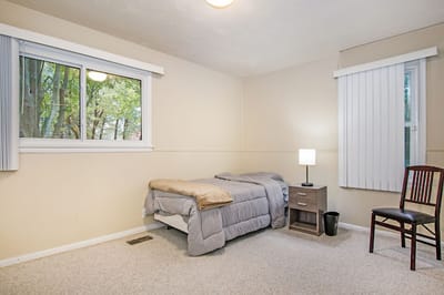 A private resident room with a bed and chair